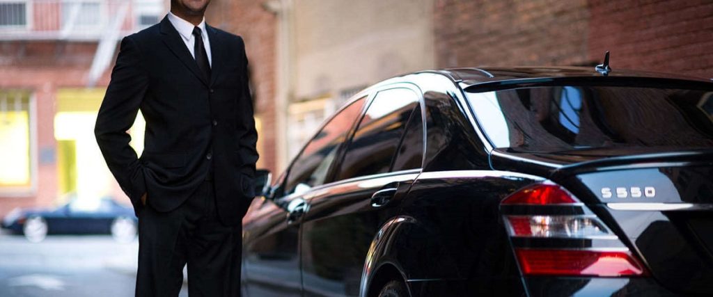 Carro executivo preto com motorista profissional esperando pelo passageiro na porta do hotel. Serviço de transfer executivo com conforto e sofisticação.